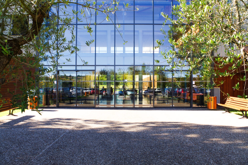 Plan serré sur l'entrée de la Clinique, façade vitrée et ensoleillée